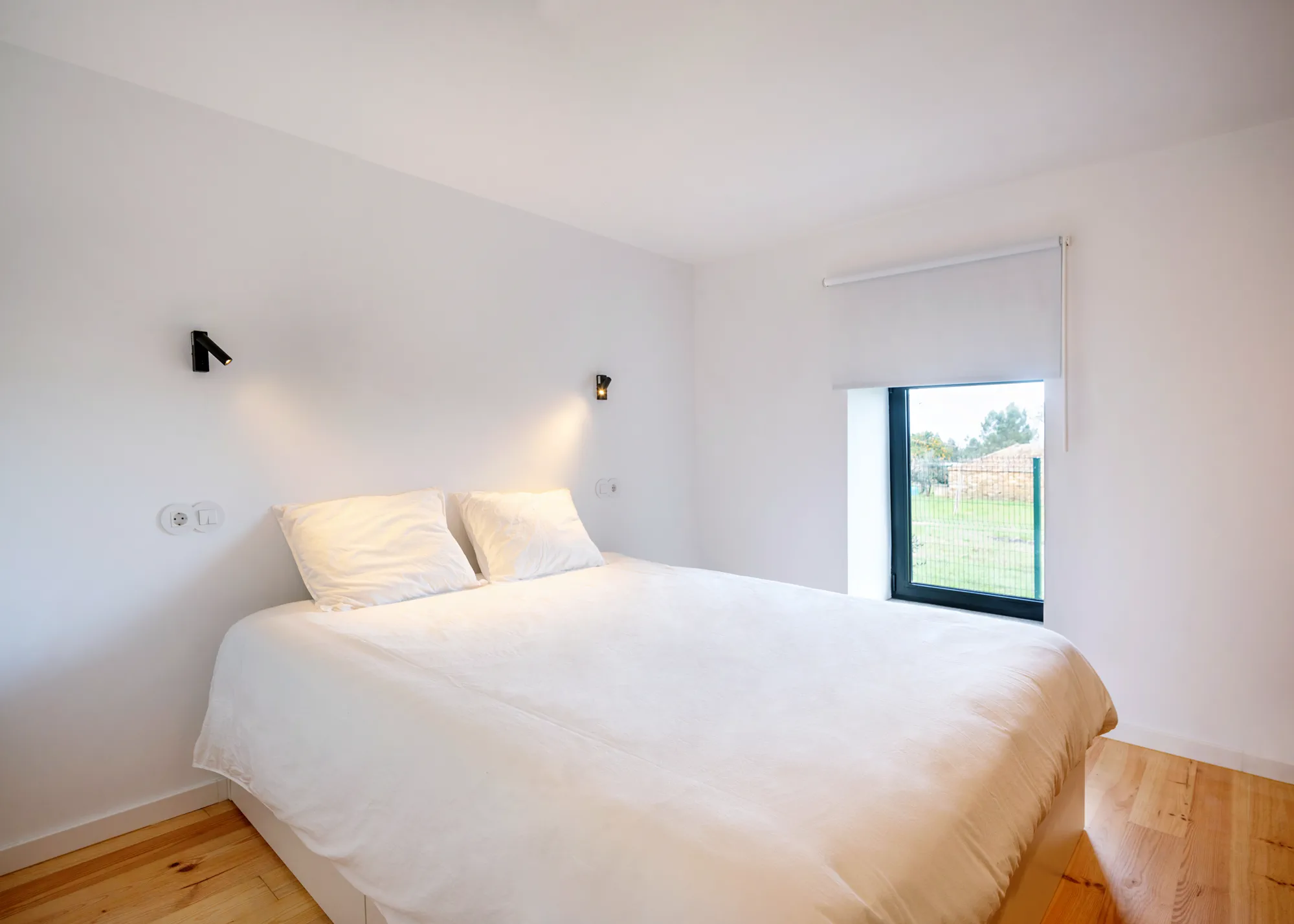 Guest bedroom with soft light, white walls, and timber floor